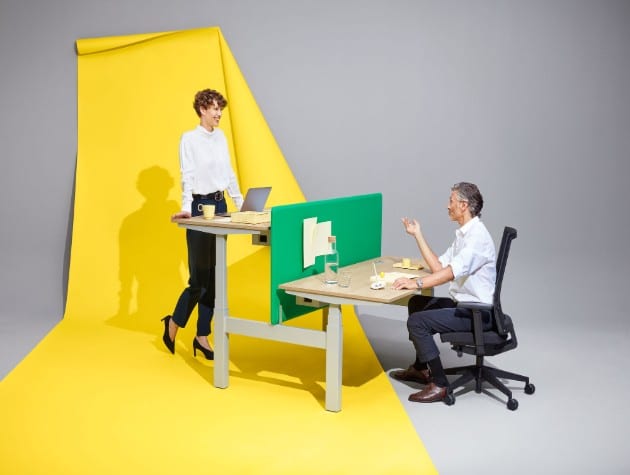 A man and woman chatting over desks of different heights
