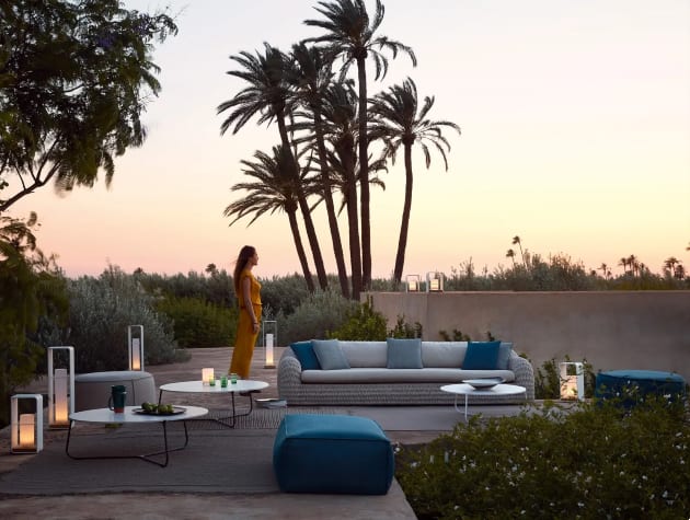 woman in garden with furniture, lights and palm trees