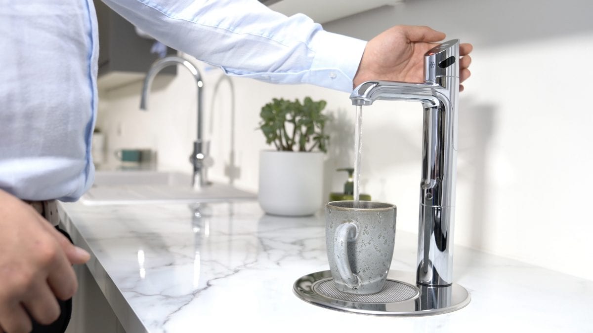 man filling cup from instant boiling water tap